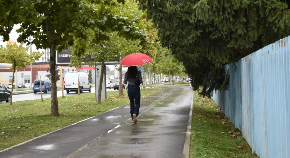 Kišni dan u gradu, mokra saobraćajnica, kapljice kiše i prolaznici sa kišobranima stvaraju autentičnu atmosferu jesenje svakodnevice. Savršena ilustracija za teme poput vremena, gradske svakodnevice i urbane fotografije.