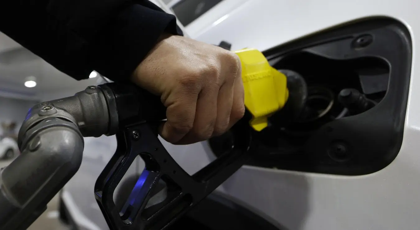 Мушкарац сипа гриво у аутомобил.