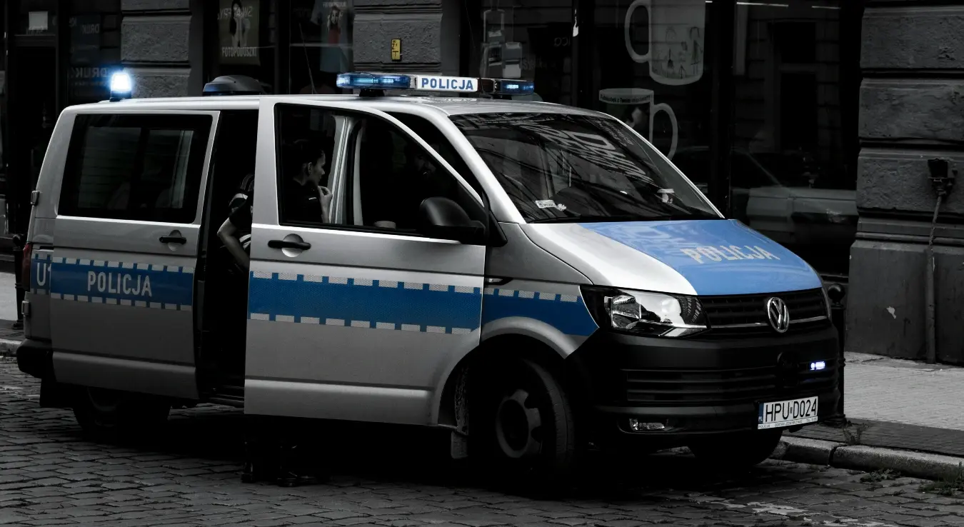 Возило хрватске полиције паркирани на улици испред зграде, врата возила су отворена.