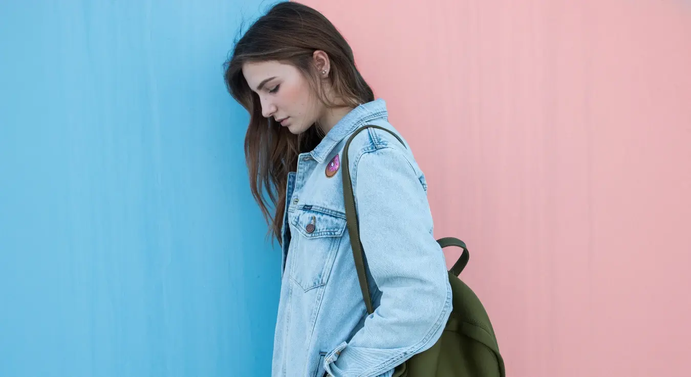 Жена у тексас јакни са руксаком на рамену.