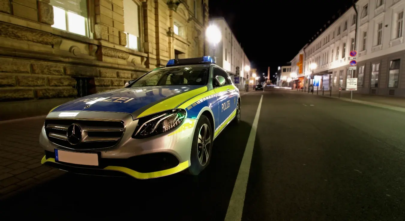 Ауто њемачке полиције паркирано на улици поред зграде.