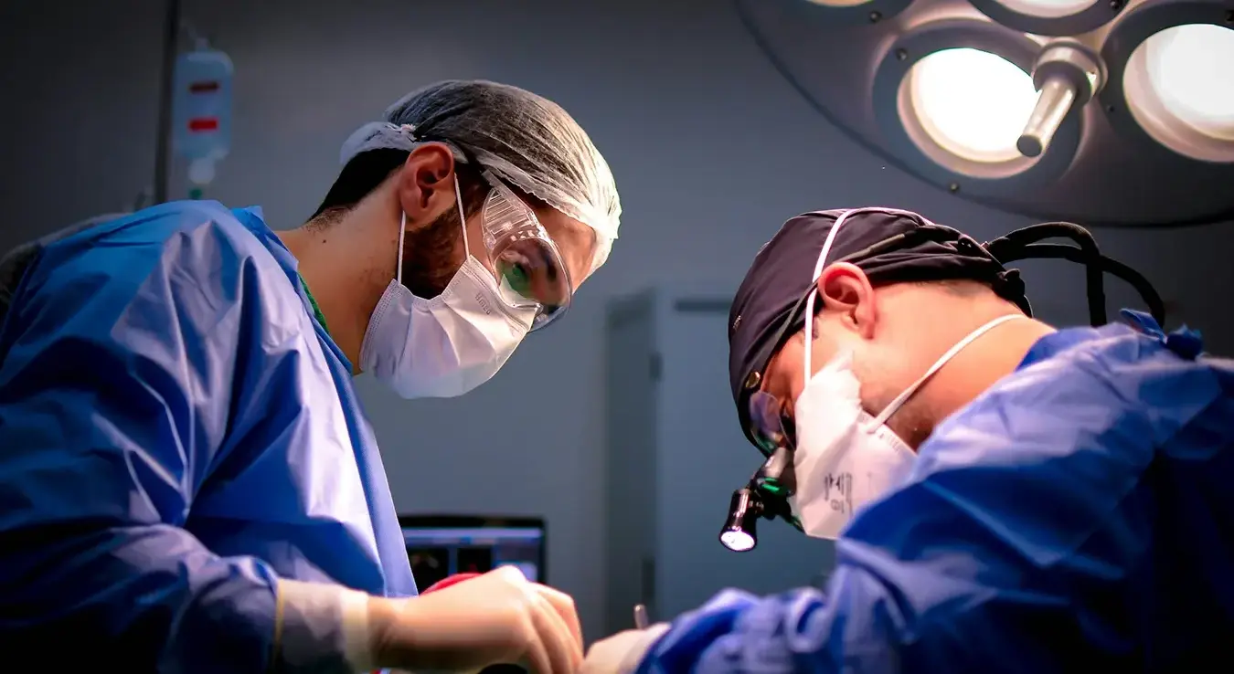 Двојица мушкараца хирирга у операционој сали оперишу.