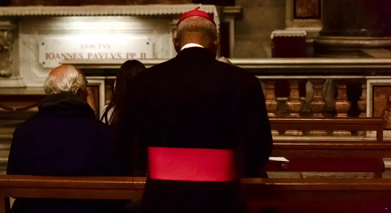 Католички свештеник окренут леђима стоји у цркви и моли се.