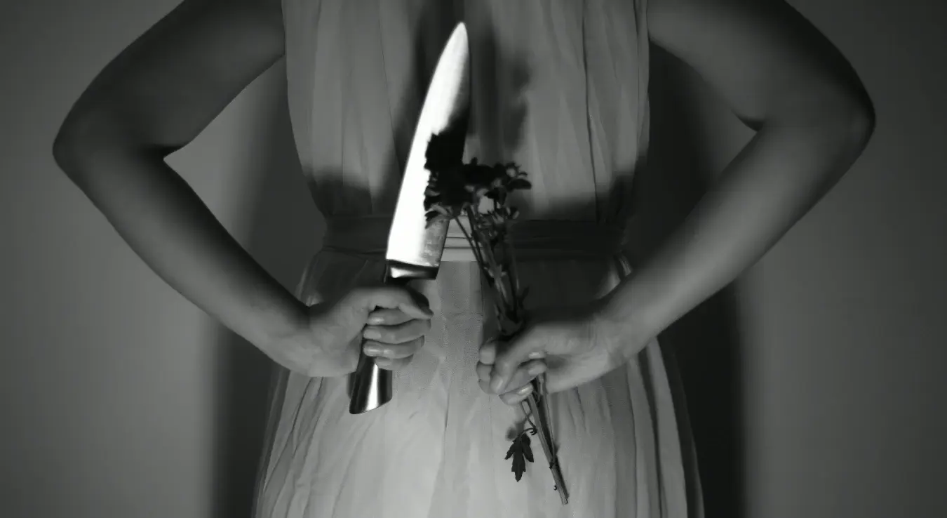 Жена у хаљини држи нож и цвијеће у руци