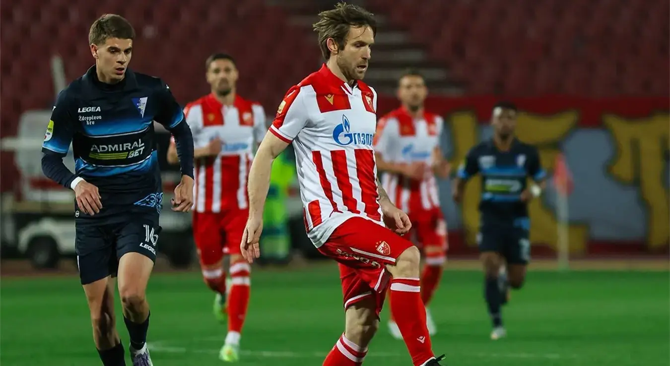 Српски фудбалер Срђан Мијаиловић у бијелом дресу ФК Црвена звезда води лопту у нападу свог тима.