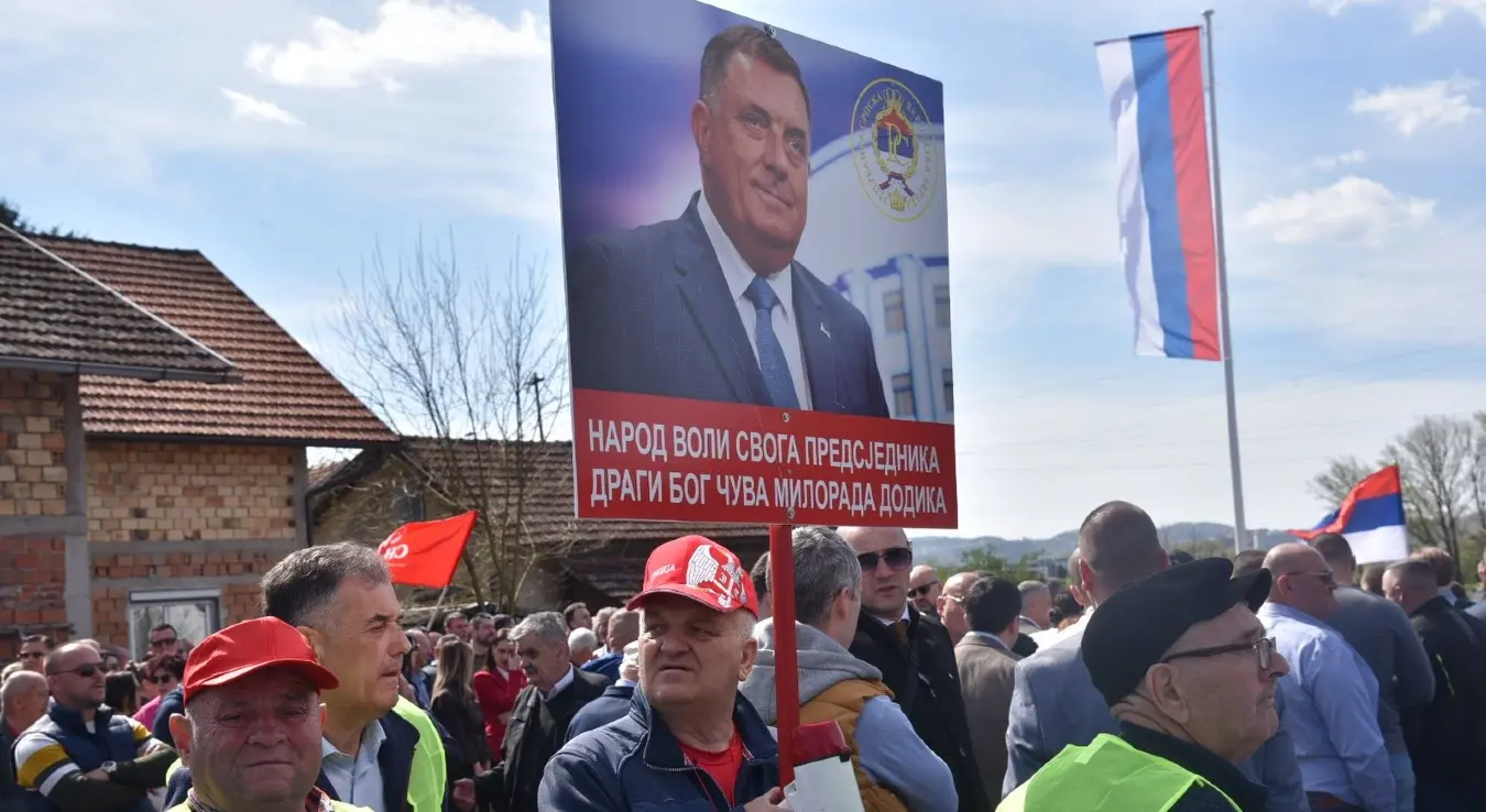 Отварање моста у Чесми. Човјек стоји напријед са транспарентом Додика са натписом "Народ воли свог драгог предсједника. Драги Бог чува Милорада Додика."