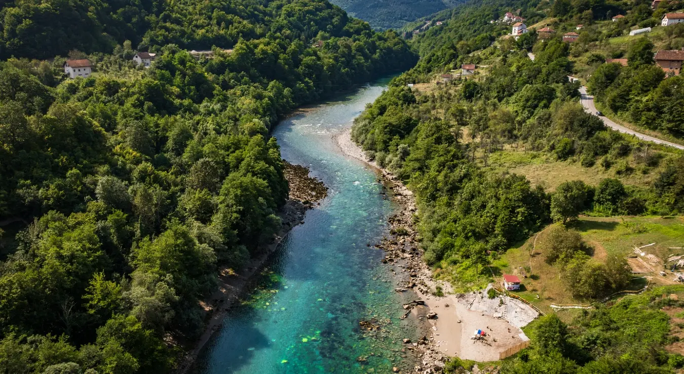 Околина Фоче. Ријека Тара окупана сунцем, окружена брдима и шумом током прољећног дана.