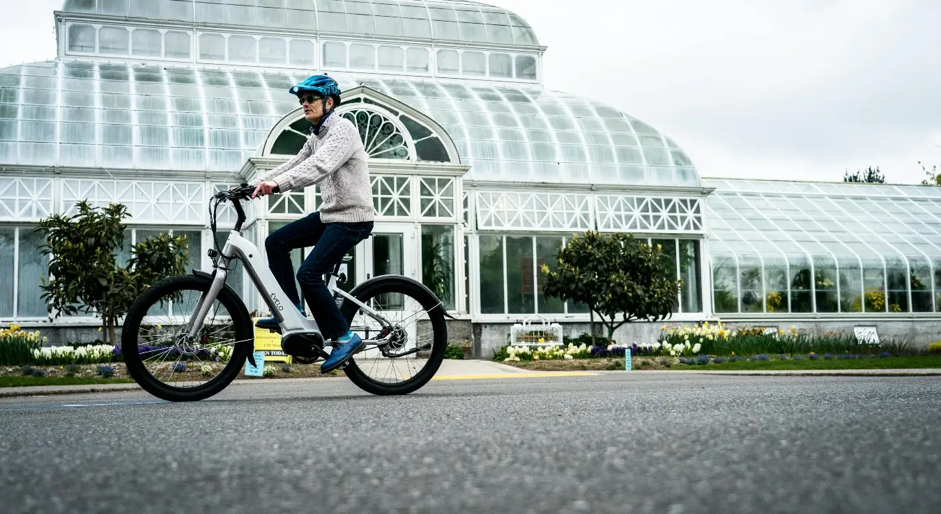 Жена вози електрични бицикл са кацигом на глави.