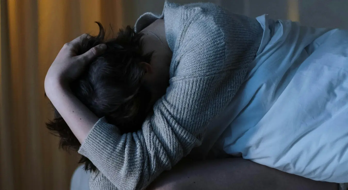 Жена погинута главом на кољенима сједи на кревету због проблема са сном