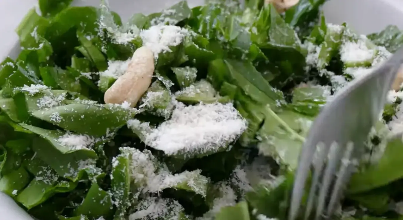 Салата од сријемуша сервирана у тањиру са индијским орасима и наренданим сиром.