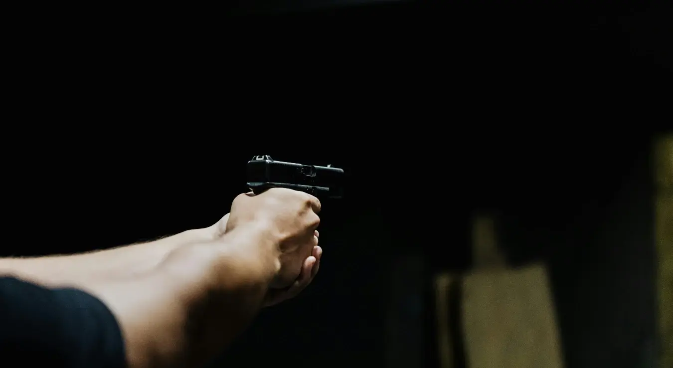 Особа држи пиштољ у рукама, спрема се да пуца