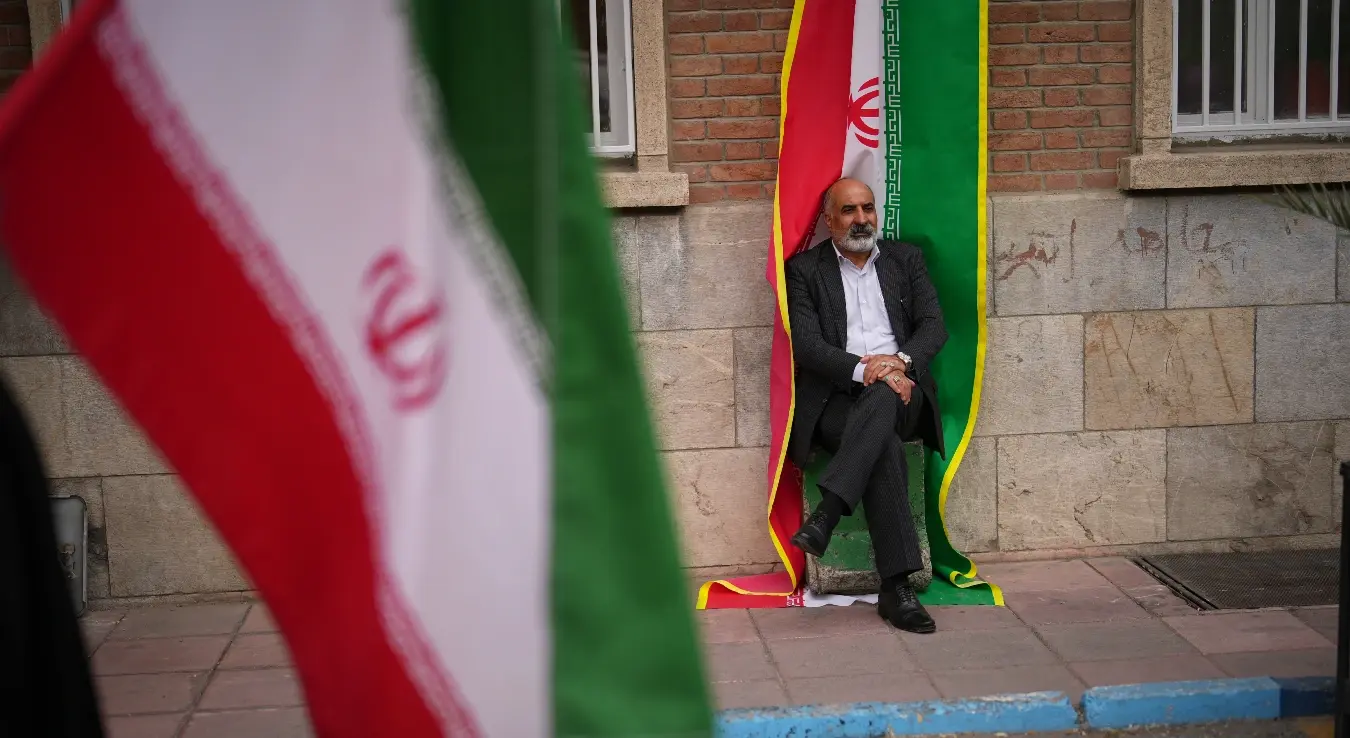 Човјек сједи поред иранске заставе током протеста који је спонзорисала влада, а којем су присуствовали медицински радници против америчко-израелске војне кампање испред болнице Имам Хомеини у Техерану, Иран, понедјељак, 6. априла 2026.