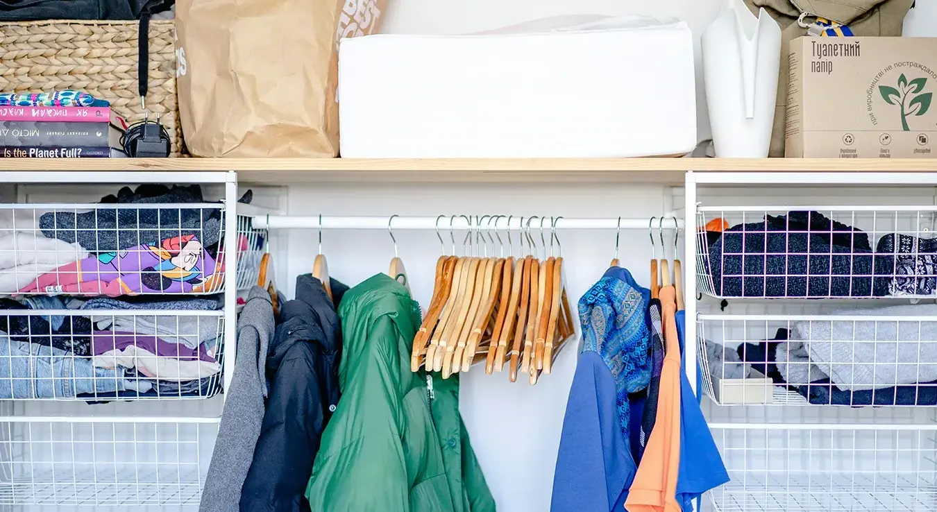 Одјећа на вјешалицама у отвореном ормару.
