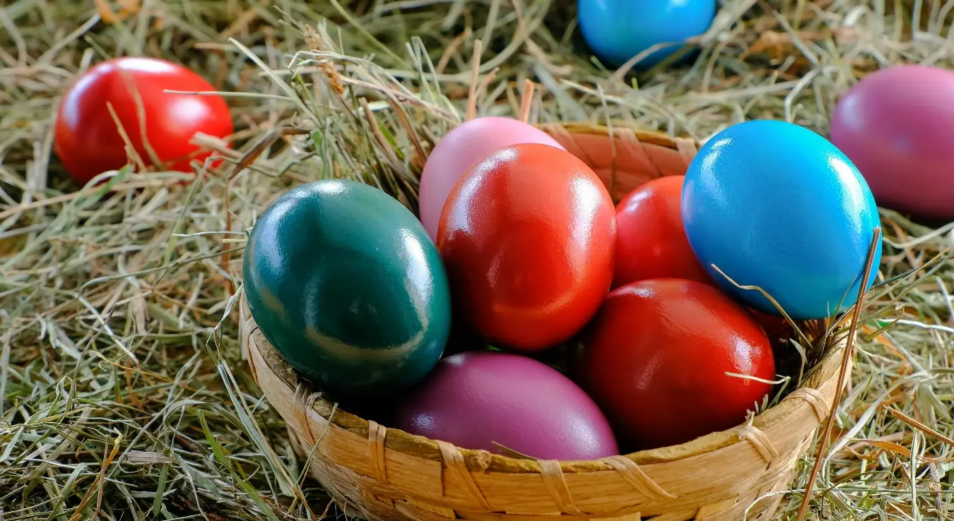 Плетена чинија са васкршњим јајима на слами.