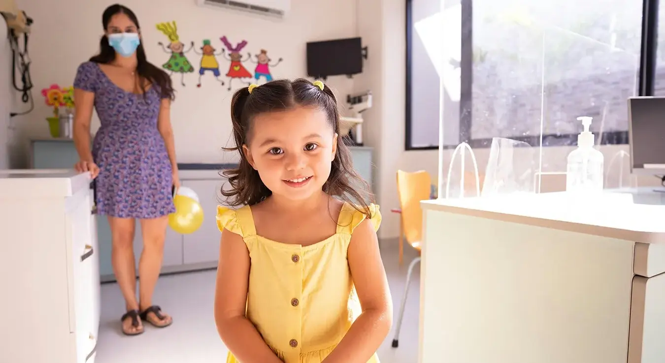 Дјевојчица у жутој хаљини стоји у болничкој соби