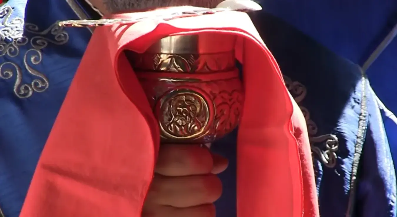 Свештеник држи чашу за причешће (путир).