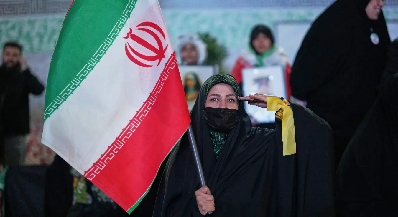 Жена салутира док држи иранску заставу током провладиног скупа на тргу у Техерану, Иран, у недјељу, 5. априла 2026. године.