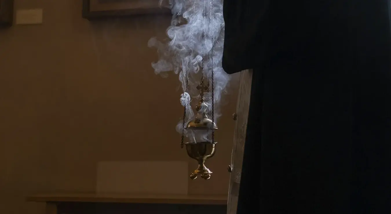 Свештеник држи кадионицу у руци.