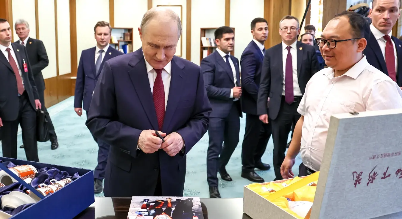 Руски председник Владимир Путин, у центру, потписује своју фотографију са кинеским инжењером Пенг Паијем, десно, снимљену током његове прве посете Кини 2000. године, у Великој кући народа у Пекингу, среда, 20. мај 2026.