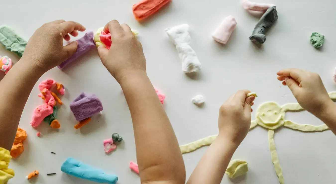 Дјечије руке праве фигуре од пластелина.