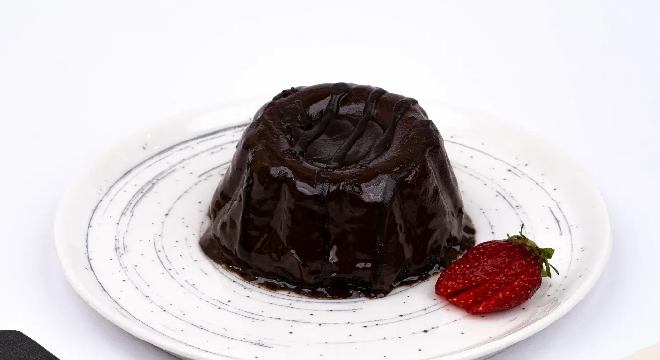 Пудинг на тањиру са декорацијом од јагода.