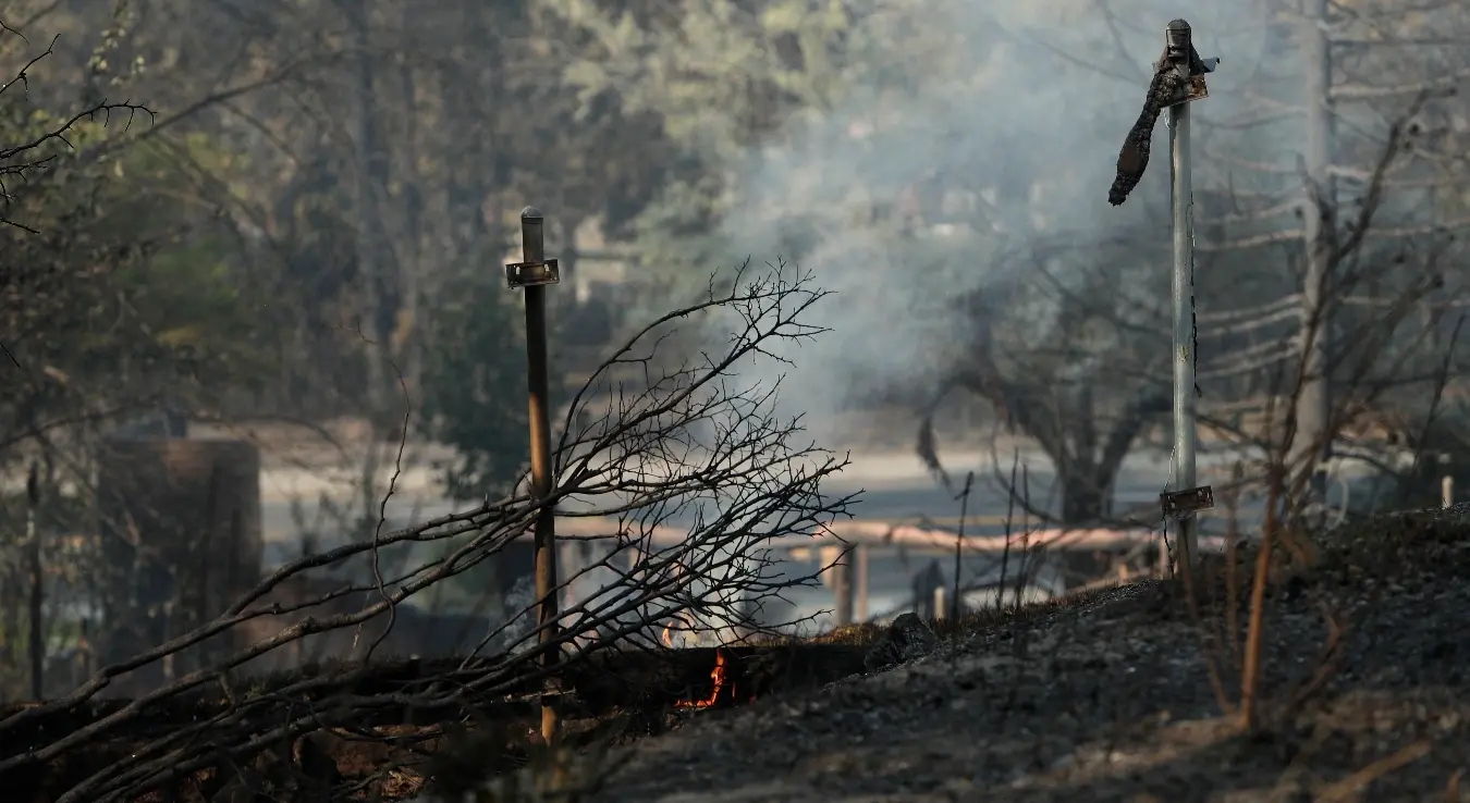 **A fallen tree continues to smolder in the Indian Trail neighborhood during wildfires, Monday, Aug. 3, 2026, in Spokane, Wash.**

Превод:

**Оборено дрво и даље тиња у насељу Индијан Трејл током шумских пожара, у понедјељак, 3. августа 2026. године, у Спокену, у савезној држави Вашингтон.**

(„Smolder“ значи **тињати, димити се без пламена**, односно дрво још гори жаром након пожара.)
