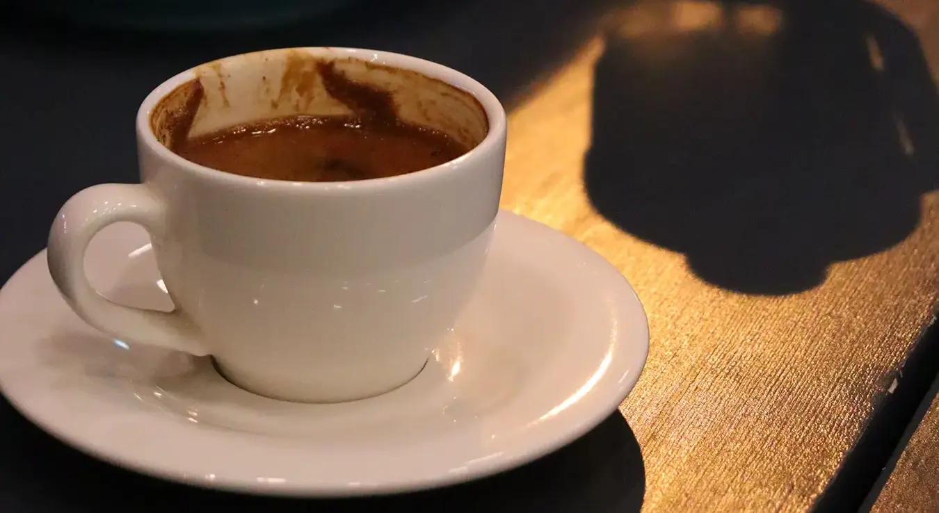 Крупни план шољице за кафу на тацни, на дрвеном столу.