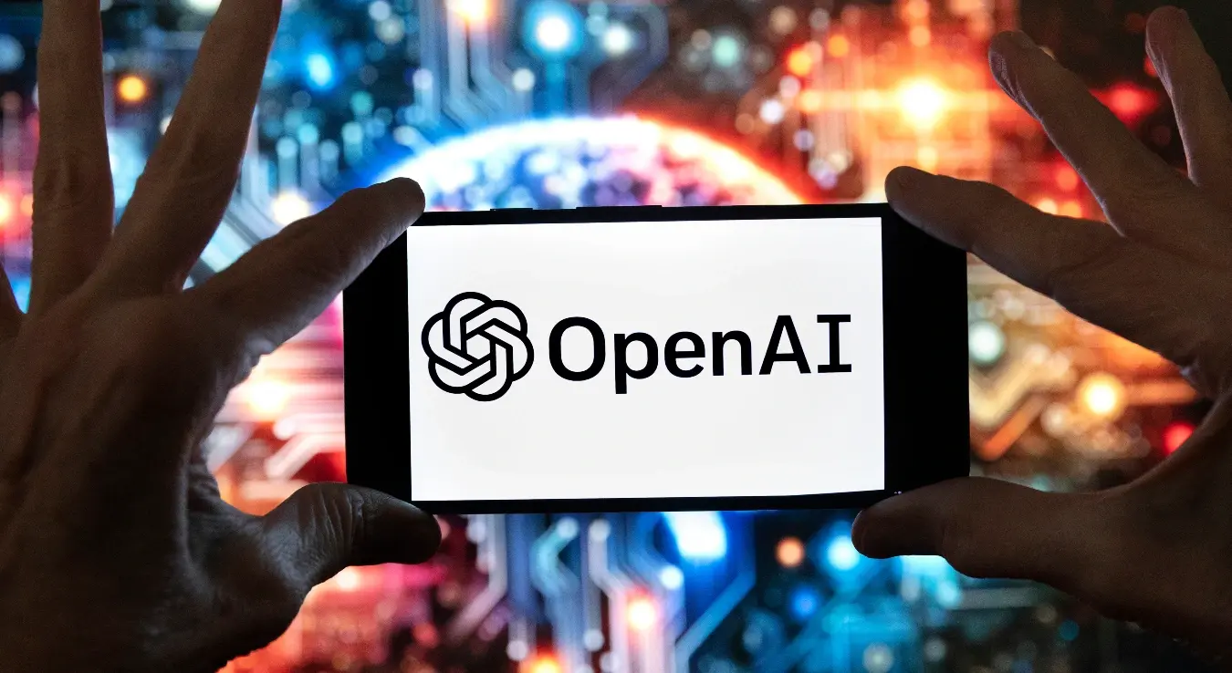 Логотип компаније OpenAI приказан је на мобилном телефону испред слике коју је генерисао модел Dall-E (који претвара текст у слику) компаније ChatGPT, 8. децембра 2023. године у Бостону.